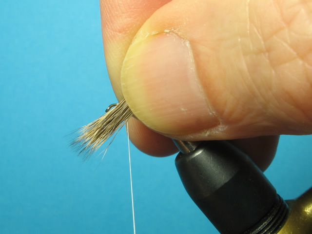 Offer the deer hair up to the hook shank - tips down, nearside at approximately 45° to the shank.